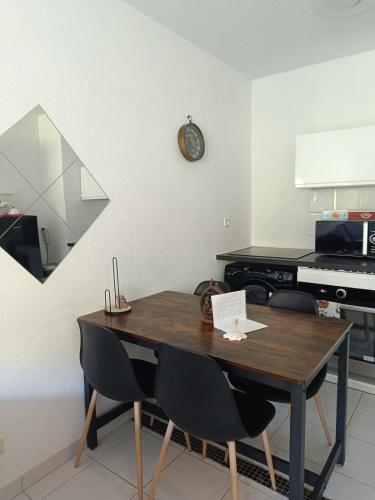 une table à manger avec des chaises et une horloge murale dans l'établissement Jolie T2 sur Menton entre Monaco et Italie, à Menton