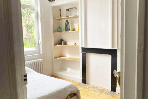 une pièce avec une cheminée, une fenêtre et un lit dans l'établissement Large Maison de ville 5 chambres avec jardin saint maur proche centre ville lille, à La Madeleine