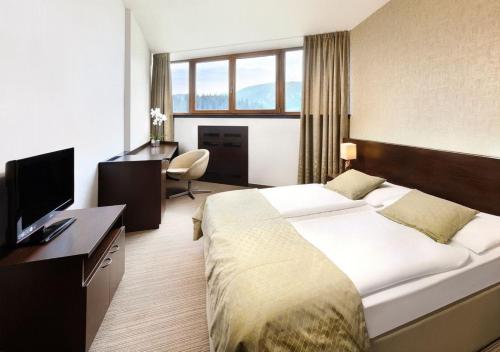 a hotel room with a large bed and a desk at Hotel Grand Jasná in Demanovska Dolina