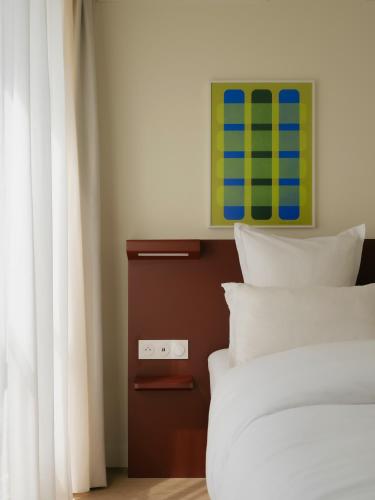 a bed with white pillows and a green painting above it at Edgar Suites - Église in Paris