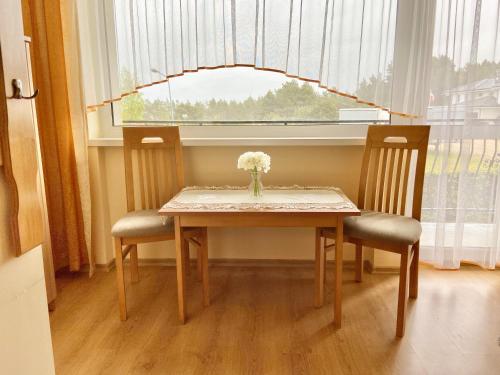 a dining room table with two chairs and a vase of flowers at Podlesie in Ostrowo