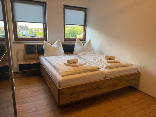 a bedroom with a bed with white sheets and two windows at K38 Mühlgrabenblick by Selected Rooms in Eisenach