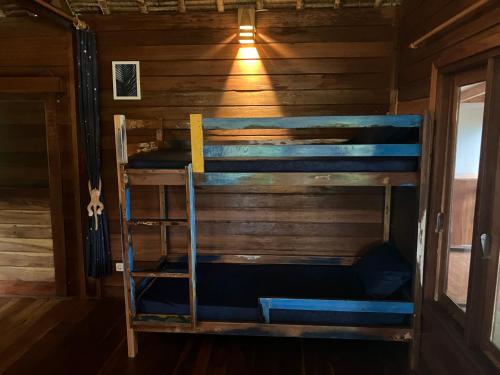 a bunk bed in a wooden cabin with a window at Taman Fajar Gili Asahan in Gili Asahan