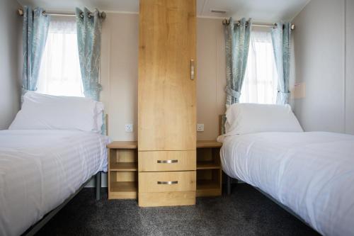 a bedroom with two beds and a wooden cabinet at Barmouth Bay Holiday Park in Barmouth