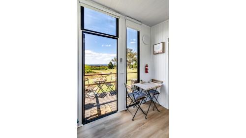 a room with a balcony with a table and a window at Gold Fields by Tiny Away in Ross Creek