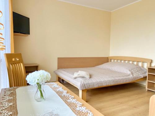 a bedroom with a bed and a table with a vase of flowers at Podlesie in Ostrowo