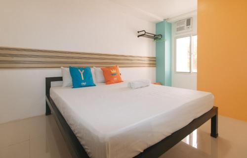 a bedroom with a large white bed with colorful pillows at Sans Hotel near Enchanted Kingdom Santa Rosa Laguna in Santa Rosa