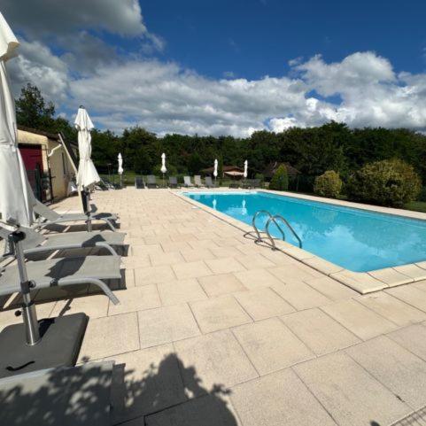 - une piscine avec des chaises et des parasols devant dans l'établissement Hameau du Soleil - Papillon, à Sainte-Mondane