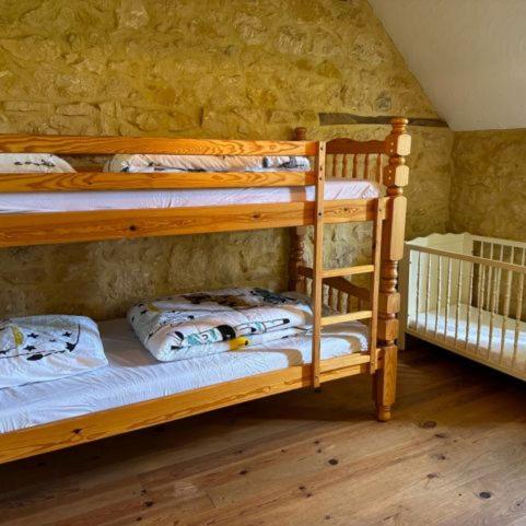 Ce lit se trouve dans un dortoir doté de 2 lits superposés et d'un mur en pierre. dans l'établissement Hameau du Soleil - Papillon, à Sainte-Mondane
