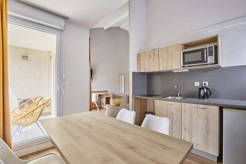 a kitchen and dining room with a table and chairs at Appart Hotel Odalys City Aix en Provence Le Clos de la Chartreuse in Aix-en-Provence