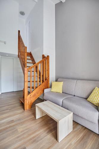 a living room with a couch and a staircase at Appart Hotel Odalys City Aix en Provence Le Clos de la Chartreuse in Aix-en-Provence
