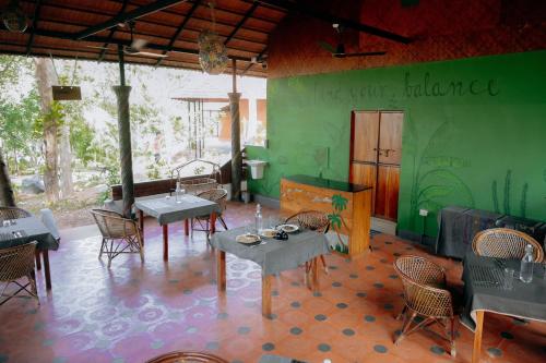 a restaurant with tables and chairs and a green wall at Vishram Village in Varkala