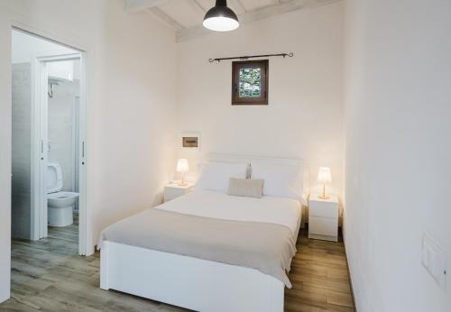 a white bedroom with a white bed and a bathroom at Il Patio sul Mare by Quokka 360 - 5 min walk from the beach in Lido Signorino