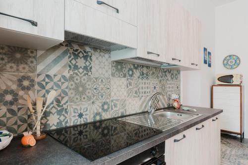 a kitchen with a sink and a tile wall at La Vanedda in Partanna
