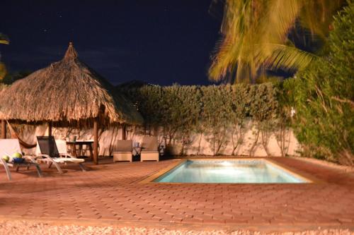 a swimming pool with chairs and a hacienda at Tropical villa Curoyal near the beach in Jan Thiel