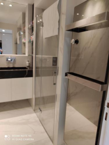 une salle de bain avec une douche avec une porte vitrée dans l'établissement Coeur Marina Baie des Anges, between Nice and Cannes, à Villeneuve-Loubet