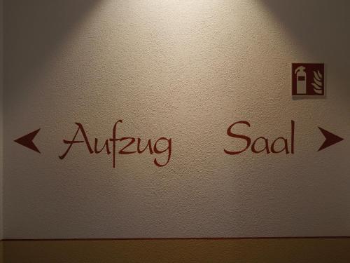 a white wall with a sign on it with arrows at Gasthof Hillig in Bad Gottleuba