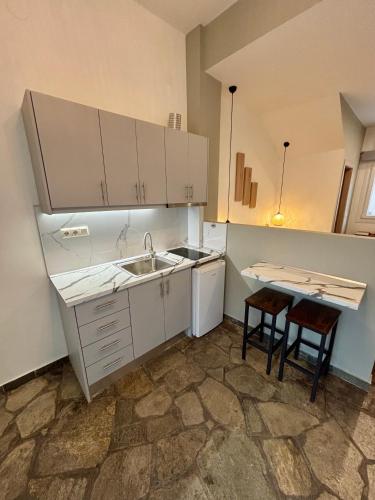 a kitchen with white cabinets and a sink and two stools at Haus Viktoria 4 in Limenas