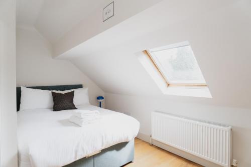 a bedroom with a white bed and a window at Duplex Redhill town centre apartment by Livingo Stays in Redhill