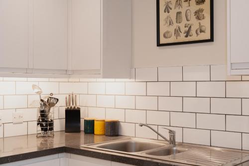 a kitchen with a sink and white tiled walls at Duplex Redhill town centre apartment by Livingo Stays in Redhill