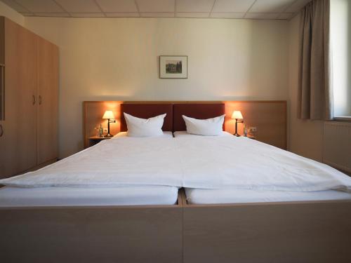 a large bed with white sheets and two pillows at Gasthof Hillig in Bad Gottleuba