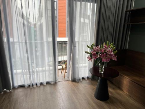 a vase of flowers on a table in front of a window at Ocean Park Homestay in HÆ°ng YÃªn