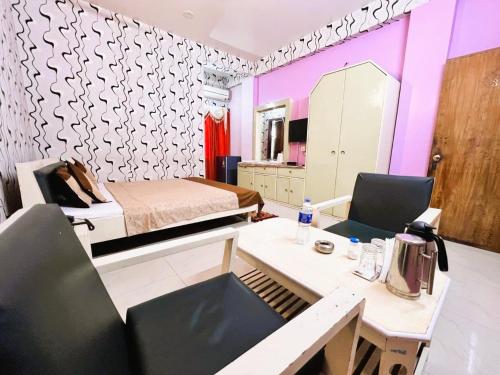 a room with a bed and a table and chairs at Hotel Ellora In Cooch Behar in Koch Bihār
