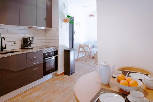 a kitchen with a table with a bowl of oranges on it at Mar-Ria 5 in Fuzeta