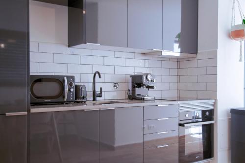 a kitchen with a microwave and a tv on the counter at Mar-Ria 5 in Fuzeta
