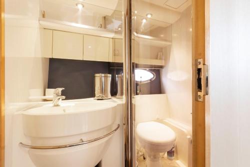 Un baño con un lavabo blanco y un inodoro. en Lux 8Br Thamesfront Villa w Yacht & Sauna, en Staines