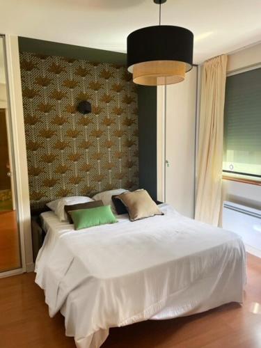 a bedroom with a bed with white sheets and pillows at Charmant Studio au coeur de Castanet-Tolosan in Castanet-Tolosan