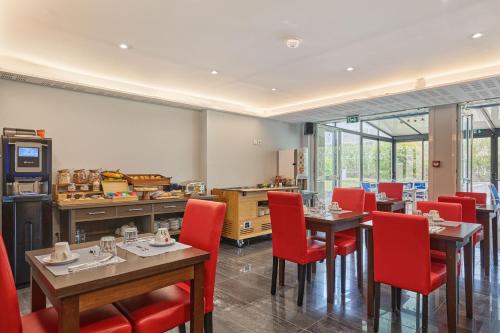 a restaurant with wooden tables and red chairs at Appart Hotel Odalys City Aix en Provence Le Clos de la Chartreuse in Aix-en-Provence