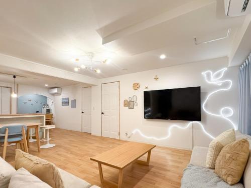 a living room with a couch and a tv on a wall at Liminal Retreats NAGOYA in Nagoya