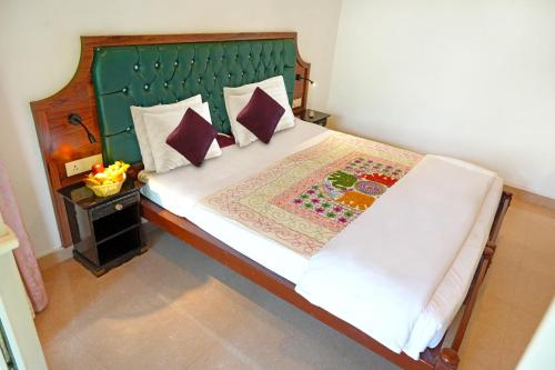 a bedroom with a bed with a green headboard and pillows at Vishram Village in Varkala