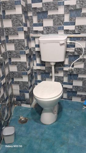 a bathroom with a white toilet in a tile wall at Maa Sheetala Dormitory in Varanasi