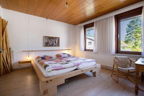 a bedroom with a bed and a desk and two windows at Die Kleine Ferienvilla in Wesselburen