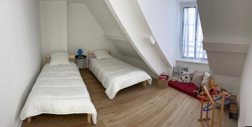 deux lits dans une chambre aux murs blancs et au parquet dans l'établissement Duplex au cœur de Paramé, à Saint-Malo