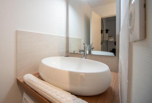 ein weißes Badezimmer mit Waschbecken und Spiegel in der Unterkunft La Citadine in Chalon-sur-Saône