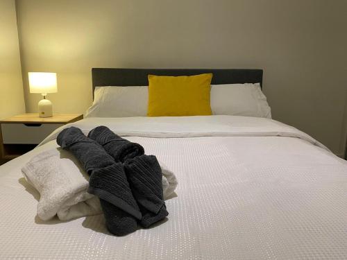 a bed with black and white towels and a yellow pillow at Cozy Suite in Clayton North