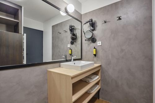a bathroom with a sink and a mirror at Appart Hotel Odalys City Aix en Provence Les Floridianes in Aix-en-Provence