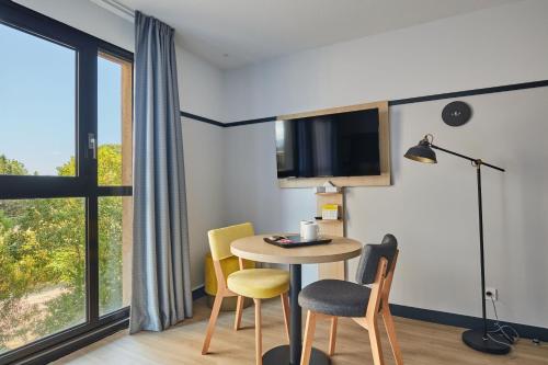 a room with a table and chairs and a window at Appart Hotel Odalys City Aix en Provence Les Floridianes in Aix-en-Provence