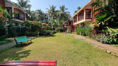 a green bench sitting in the grass next to some buildings at Royale Holiday Villa - 4BHK JAQK Holidays in Baga
