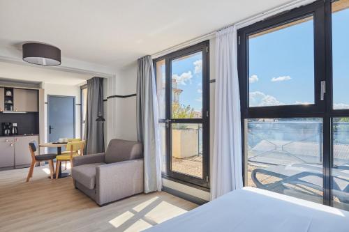 a hotel room with a bed and a chair and a window at Appart Hotel Odalys City Aix en Provence Les Floridianes in Aix-en-Provence