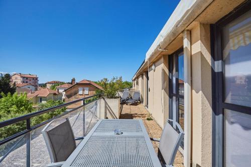 a patio with a table and chairs on a balcony at Appart Hotel Odalys City Aix en Provence Les Floridianes in Aix-en-Provence