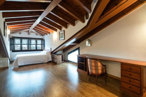 ein Schlafzimmer mit einem Bett und einem Schreibtisch auf einem Dachboden in der Unterkunft Casa el Balandro de Poo in Llanes