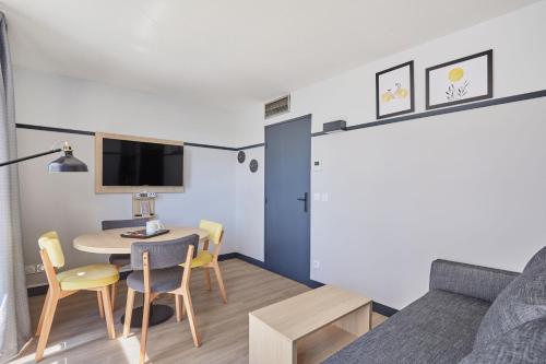 a room with a bed and a table and chairs at Appart Hotel Odalys City Aix en Provence Les Floridianes in Aix-en-Provence