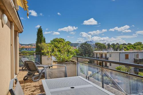 a balcony with a table and chairs and a view at Appart Hotel Odalys City Aix en Provence Les Floridianes in Aix-en-Provence