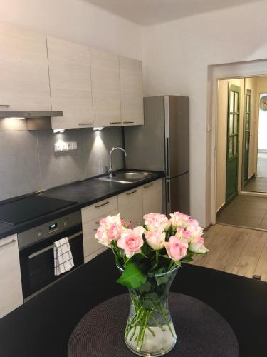a vase of pink roses on a table in a kitchen at Apartmány CAFÉ-CAFÉ in Jičín
