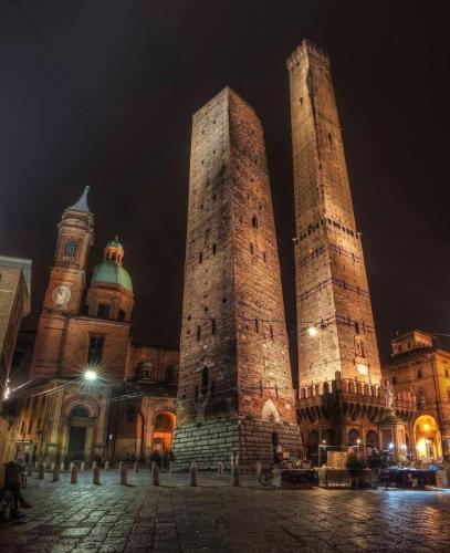 two tall towers in front of a building at night at Suite privata con terrazza in Bologna