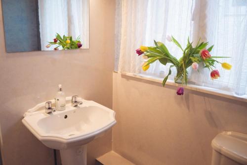 a bathroom with a sink and a window with flowers at Ardtalnaig House, Loch Tay in Ardtalnaig